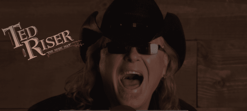 Person wearing a black hat and sunglasses, mouth open in surprise or excitement.
